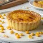 Corn egg tart served on a plate with golden crust and creamy center